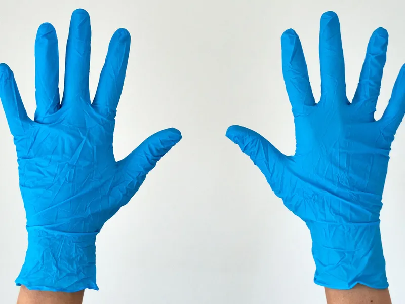 Two open hands wearing blue disposable gloves; illustrative glove-use photography.