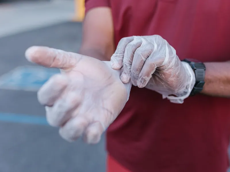 Close-up of a person putting on a translucent disposable glove; illustrative glove-use photography.