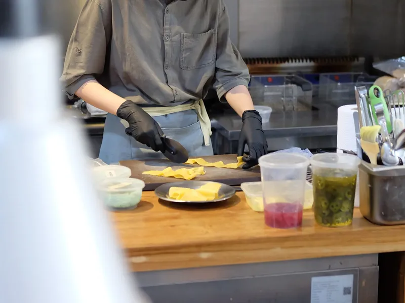 Chef in gloves preparing food at a professional restaurant workstation.